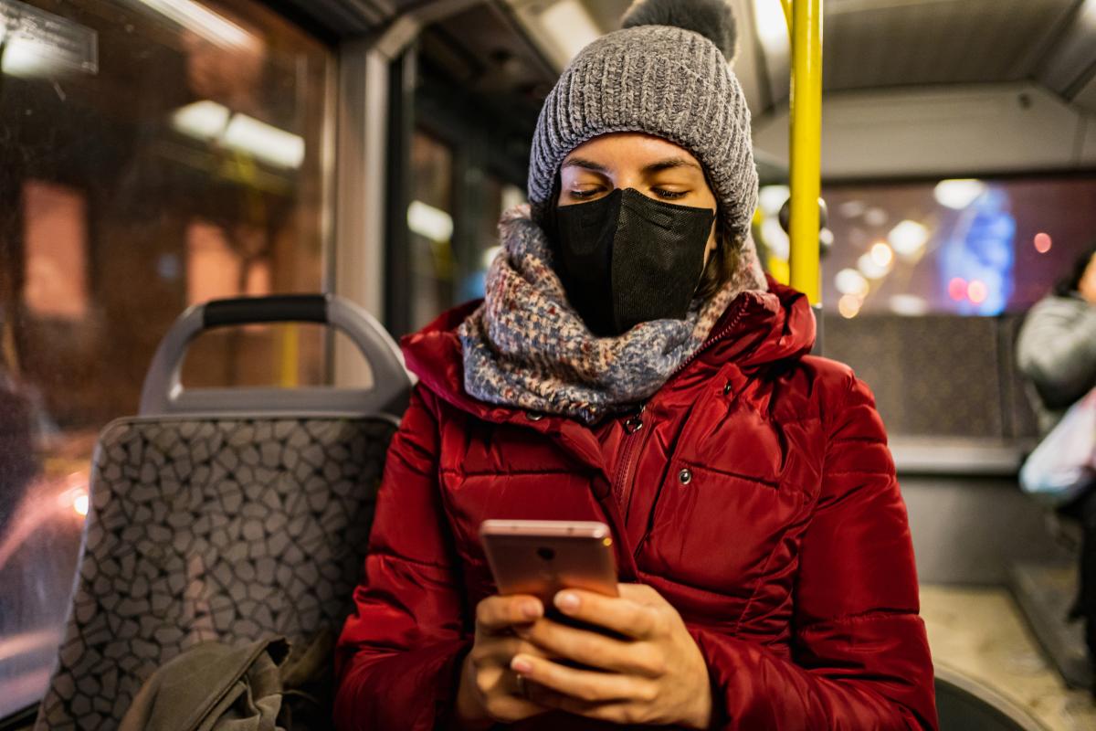 COVID-19 depiction. Woman on a bus wearing a black face mask.